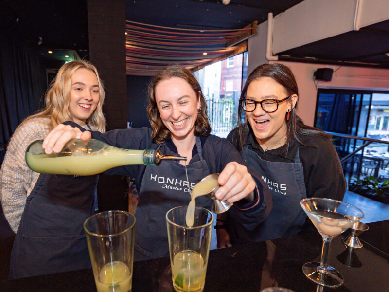 People laughing whilst making cocktails at a cocktail class